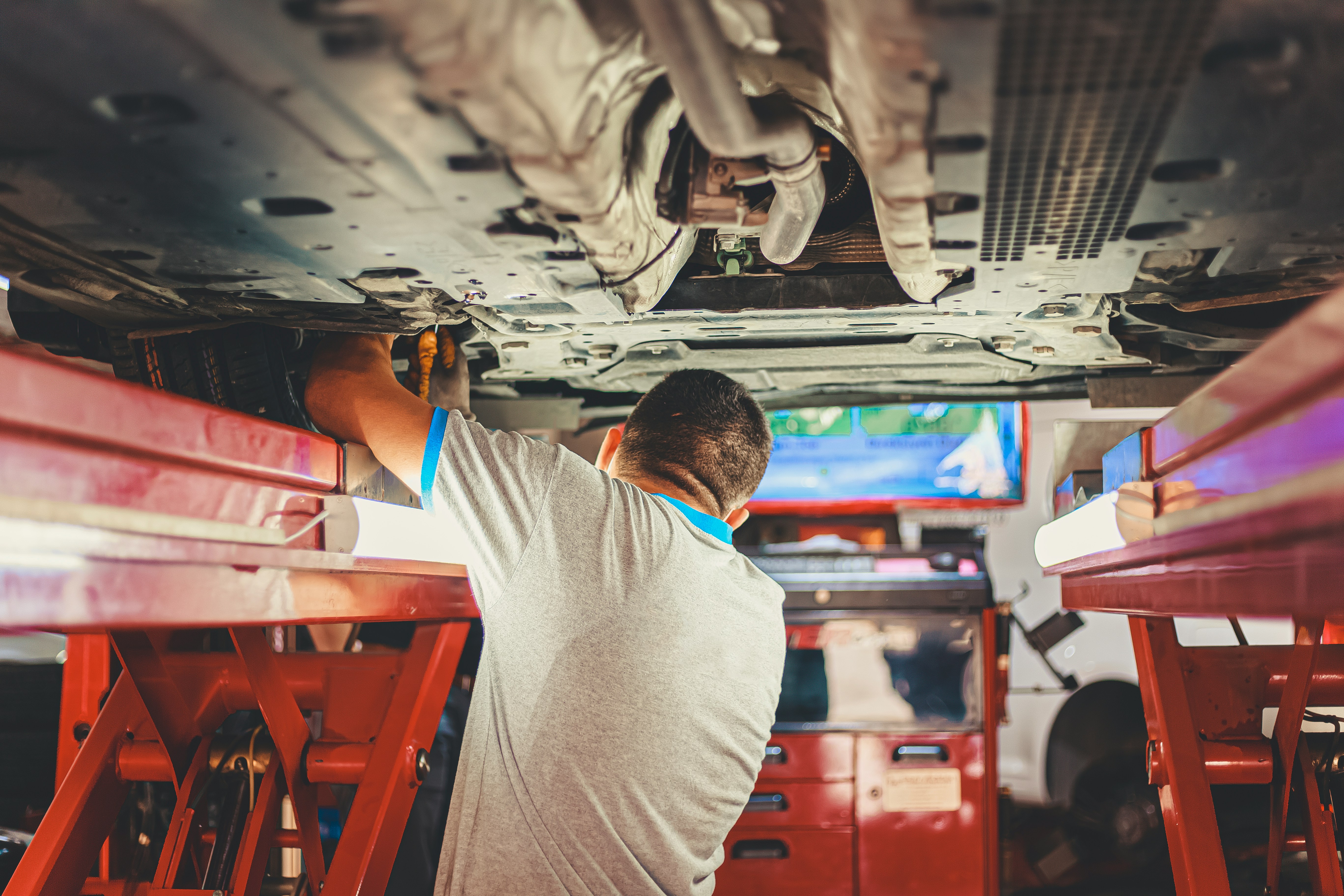 Monteur werkt onder een opgehesen auto in de werkplaats
